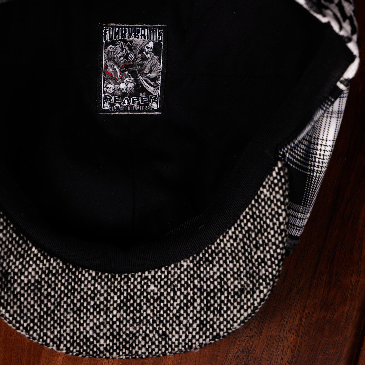 Close-up of a black snapback cap with a black and white patterned visor and a square embroidered patch on the side featuring a skull graphic and the text 'FUCK BEAMS' and 'PENTACON'.