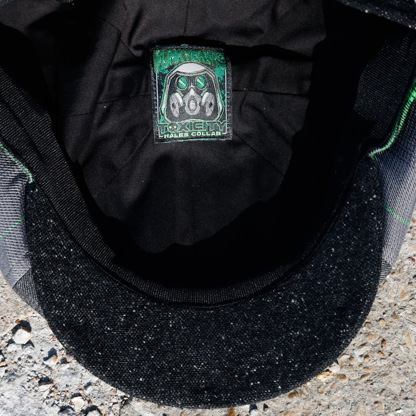 Close-up of the inside of a black cap showing a square patch label with a gas mask graphic and the text 'TOXICITY' and 'HALES COLLAB'.