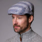 Man wearing a checkered cap and gray sweater against a gray background
