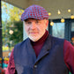 The Troubadour houndstooth newsboy cap worn with a burgundy turtleneck and dark vest, front view.