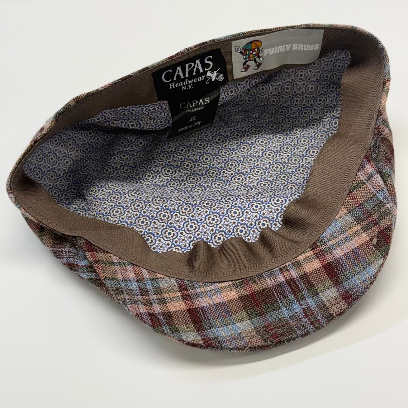 Plaid flat cap with patterned interior on a white background