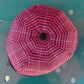 A pink and black patterned dome tent viewed from directly above, resting on a teal metal surface with circular cutouts.