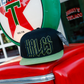 Wretch black snapback with green bill and outlined Hales embroidery