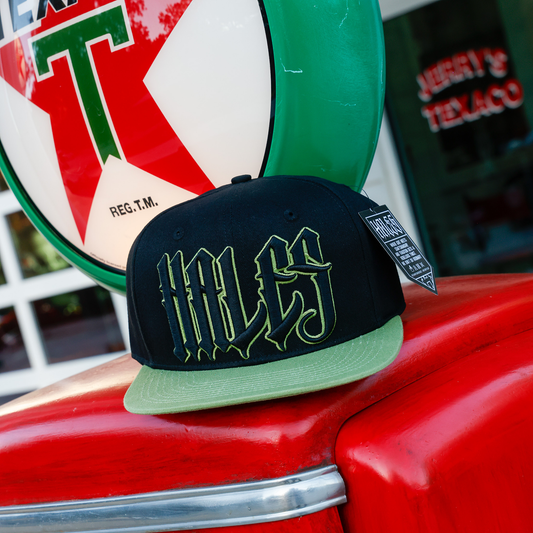 Wretch black snapback with green bill and outlined Hales embroidery